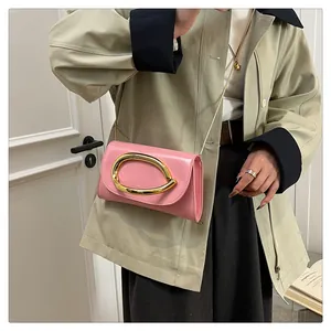 Detail of pink patent leather handbag with gold horseshoe buckle and chain strap