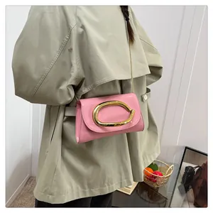 Detail of pink patent leather handbag with gold C-buckle on a khaki trench coat