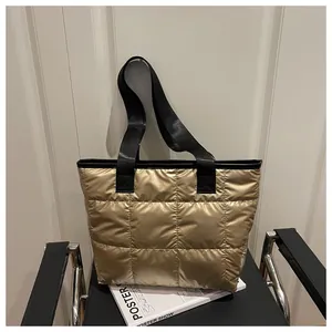 Detailed view of gold quilted puffer tote bag with black straps on a black metal chair