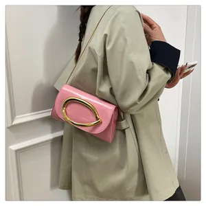 Detail of pink patent leather handbag with gold oval buckle and metal chain strap