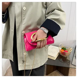 Detail of magenta patent leather handbag with luxury gold irregular metal handle