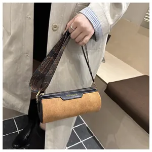 Detail of cylinder bag showing brown suede texture and ethnic style woven strap