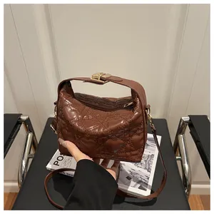 Détail du sac à main marron foncé matelassé en cœur avec ferrures dorées et poignée
