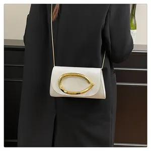 Detail of white patent leather crossbody bag with oversized gold oval buckle and chain
