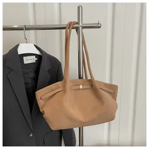 Detail of camel suede tote bag with long shoulder strap and gold metal buckle accents