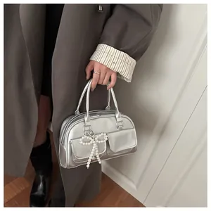 Detail of silver metallic Boston bag featuring pearl bow charm and twin front pockets