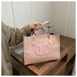 Close-up of pink tote bag featuring embossed M logo and stylish letter pattern details
