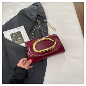 Detail of burgundy patent leather handbag with gold oval handle and chain strap