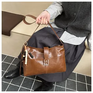 Detailed close-up of brown vintage crossbody bag with metal buckle and decorative beads