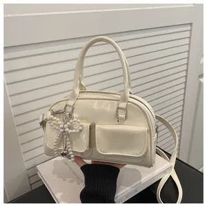 Detail of cream Boston bag with pearl bow charm and dual front flap pockets