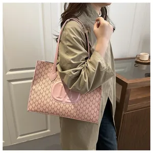 Pink tote bag with M-letter print and embossed logo shown in a lifestyle side view