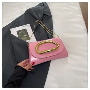 Detailed top view of pink patent leather handbag with large gold buckle and chain strap