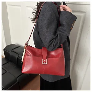 Detail of red faux leather shoulder bag with silver buckle and white beaded charm