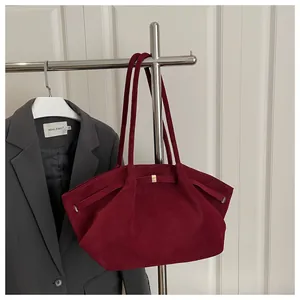 Detail of burgundy suede bucket bag with gold accents and stylish shoulder strap