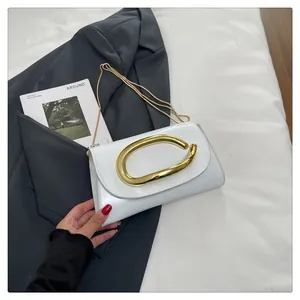 Close-up of white patent leather small square bag with golden curved metal buckle and chain