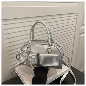 Detail of silver metallic Boston bag featuring pearl bow charm and front flap pockets