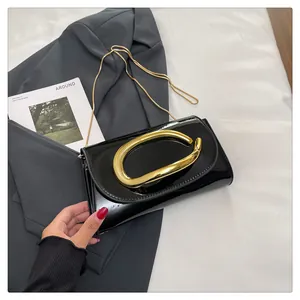 Close-up of black patent leather handbag with a unique gold metal ring and chain strap