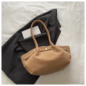 Close-up of light brown suede bucket bag with gold hardware and long handles