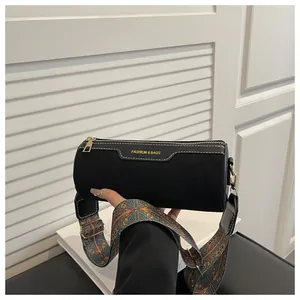 Detail of black cylindrical bag with contrast stitching and bohemian patterned strap