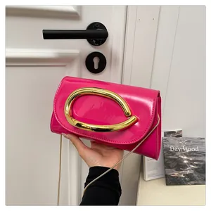 Detail of fuchsia patent leather handbag with large gold C-clasp and chain strap