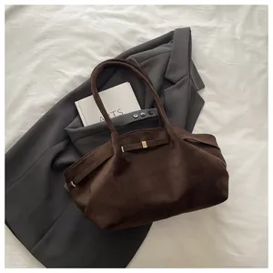 Detailed view of vintage dark brown suede bucket bag with gold buckle on white fabric