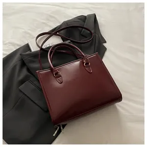 Detail of dark red glossy leather tote bag with round handles and shoulder strap