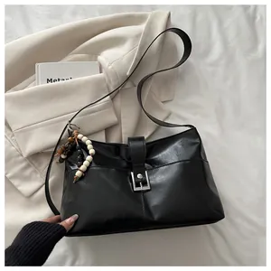 Detailed close-up of glossy black leather shoulder bag with vintage silver metal buckle