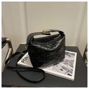 Détail du cuir matelassé en forme de cœur et du fermoir doré sur le sac bandoulière noir