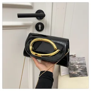 Detail of glossy patent leather handbag with gold arc handle and fine chain strap
