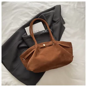 Detail showing brown suede texture and decorative buckle of the vintage bucket bag