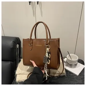 Brown leather tote bag featuring a luxury chocolate charm and golden fashion lettering