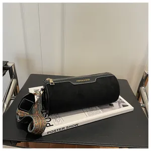 Close-up of black cylinder bag with golden zipper and colorful bohemian strap