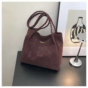 Detail der weinroten Wildleder-Tote Bag mit geflochtenen Griffen und goldenem Logo