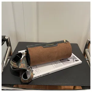Detail of cylinder bag showing brown suede and black leather patchwork with contrast stitching