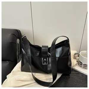 Detail of black glossy PU leather handbag featuring a silver square metal buckle closure