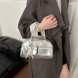 Silver metallic Boston handbag with twin pockets and pearl bow charm shown with model