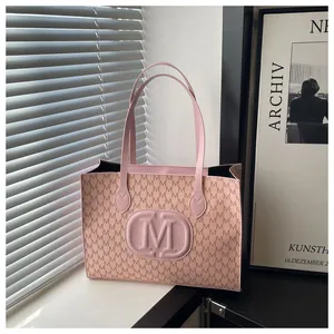Detail of pink faux leather tote with M letter monogram and embossed center logo