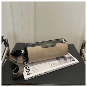 Detail of beige textured cylinder bag with black trim and bohemian pattern strap
