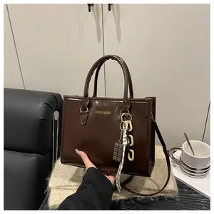Detail of glossy brown leather handbag with creative chocolate-themed charm and gold text