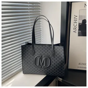 Detail of Harajuku style black tote bag featuring M-letter monogram and leather straps