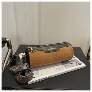 Detail of cylinder bag in brown suede and black leather with vintage patterned strap