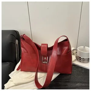 Detail shot of the retro red leather texture and metallic square buckle on the handbag