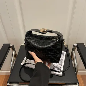 Sac à main noir matelassé en cœur avec fermoir doré et bandoulière sur une chaise