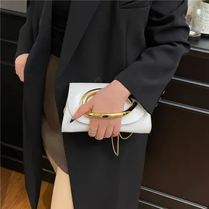 Chic white leather handbag with oversized gold circular handle and metal chain strap