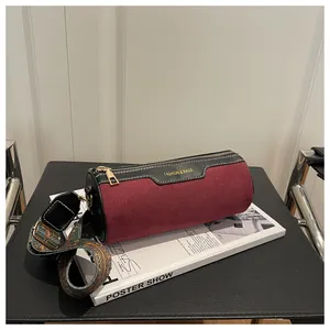 Detailed macro view of burgundy suede cylinder bag with a retro embroidered wide strap