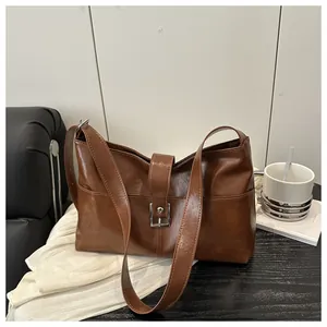 Detail of vintage brown leather handbag with silver square buckle and wide shoulder strap