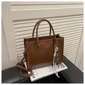 Detail of vintage brown leather handbag with gold logo and chocolate charm accessory