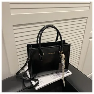 Detail of black glossy PU leather handbag with fashion text and chocolate charm decor