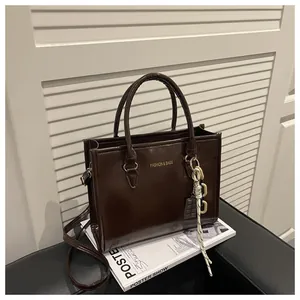 Macro view of dark chocolate polished leather tote bag with fashion text and charm