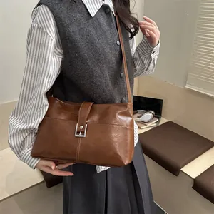 Brown vintage faux leather crossbody bag with silver buckle in a stylish model street pose